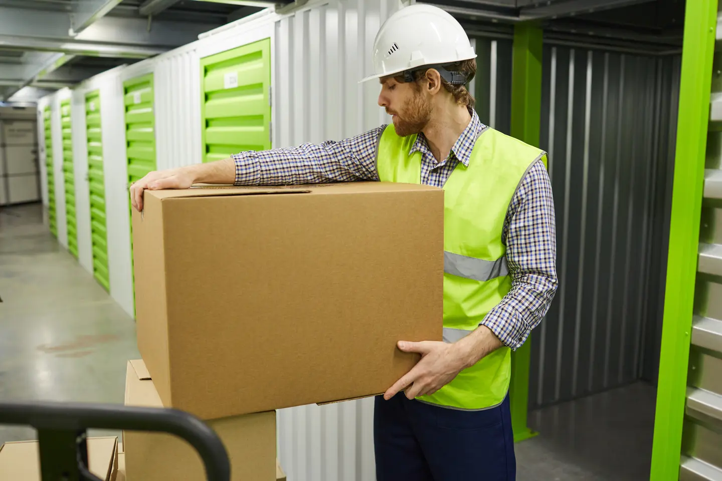 Young worker in protective workwear clothing holding big cardboard box and putting it into the chamber